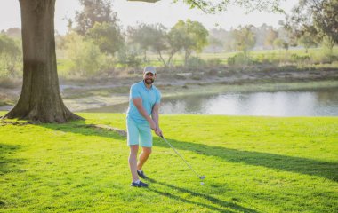 Profesyonel golf sahasında erkek golfçü. Golf sopalı bir golfçü ateş ediyor.