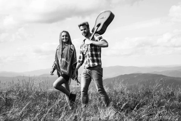 陽気な笑顔の女性とギターを持つヒップスターの男は 山で楽しい時間を過ごしています — ストック写真