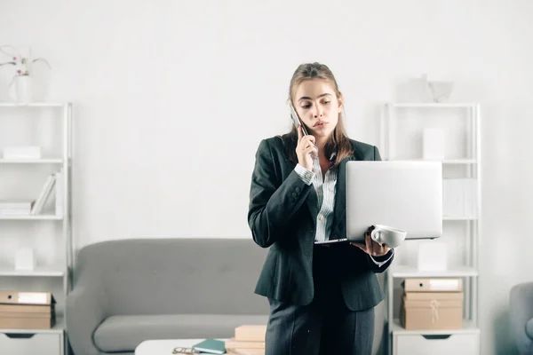 Serious business woman, office manager with phone at office desk. Businesswoman entrepreneur working in office, professional employee at workplace. Young beautiful secretary girl