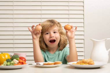 Yumurta yiyen çocuk. Küçük çocuk sağlıklı bir kahvaltı yapıyor. Çocukların beslenmesi ve gelişimi. Çocukların sebze yemesi onları daha sağlıklı yapıyor.