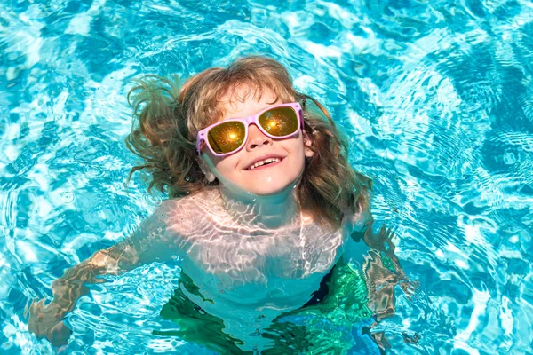 Child swim in summer pool water. Summer vacation fun. Cute kid in swimming pool