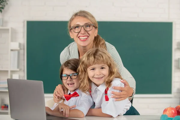 First day at school. Cute little boy from elementary school and tutor teacher studying lesson on laptop in class. School education and children concept