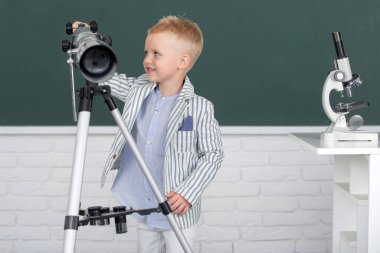 Teleskoplu okul çocuğu okulda astronomi dersi alıyor.