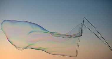 Dev renkli baloncuk. Mavi gökyüzünde büyük bir sabun köpüğü. İple kocaman sabun köpükleri. Sopalar mavi gökyüzüne karşı büyük kabarcıklar oluşturuyor. Halat ve sopalarla kabarcık oluşturur.