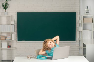 Dizüstü bilgisayar kullanan şirin bir çocuk, online e-öğrenme yoluyla okuyan bir çocuk. Küçük komik sistem yöneticisi