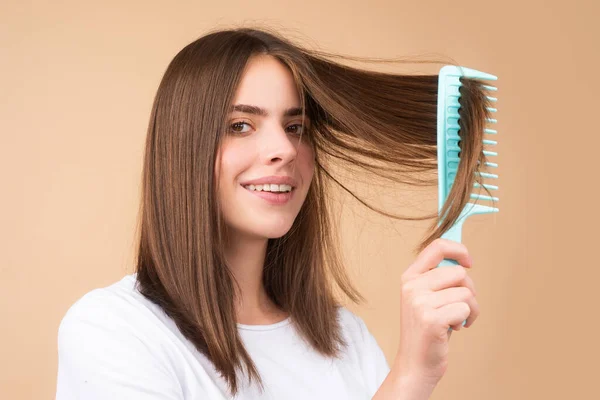 Attractive woman combing hair. Beautiful girl combs hair. Haircare concept