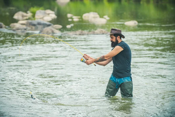 一个留着胡子的年轻人在湖边或河里钓鱼 — 图库照片
