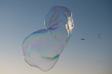 Gökkuşağı yansımalı sabun köpükleri. Mavi gökyüzünde kabarcıklar. Baloncuk partisi