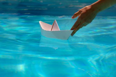 Kağıt gemi yola çıkmaya hazır. Turizm ve seyahat, seyahat hayalleri tatil tatili, yelkenli macerası. El ele tutuşan kağıttan bir tekne.