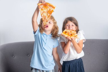 Pizza ve çocuklar, çocukların elinde pizza dilimleri. Çocuklar peynirli lezzetli fast food pizzası yiyorlar. Aç arkadaşlar için mutlu zamanlar. Komik çocuklar, küçük kız ve oğlan lezzetli pizza yiyorlar.