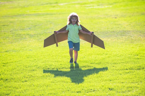 Child boy like a pilot with toy wings against blue sky. Kids freedom concept. Startup