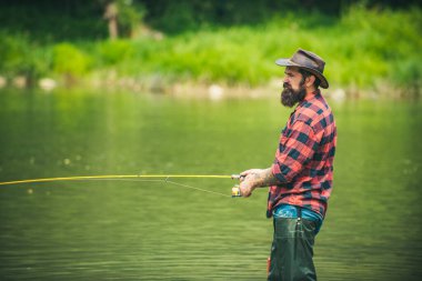 Young bearded man angler fishing at a lake or river. Flyfishing