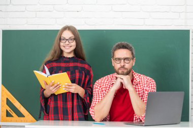 Öğretmen okul çocuğuna dersi açıklıyor. İlkokul çocukları okulda ödev yapmayı öğreniyor.