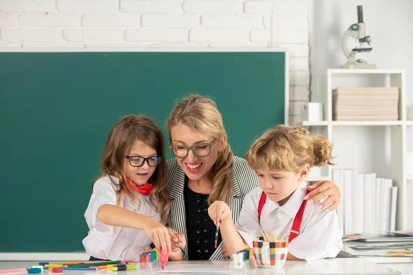 Schoolkids with teacher. Happy children from elementary school study at draw lesson. Pupils girl and boy with teacher painting at art school. Education and knowledge