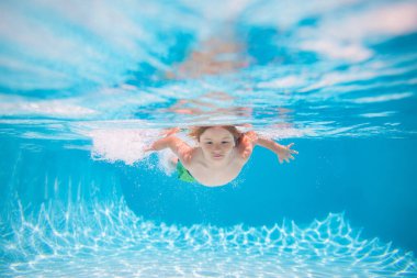 Kid boy swimming underwater on the beach on sea in summer. Blue ocean water. Child boy swimming in sea. Summer kids in sea water on beach