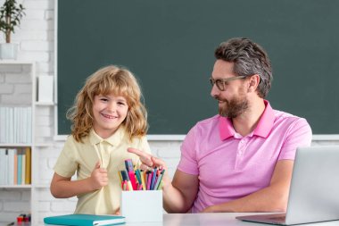 School teacher with a schoolboy. Teacher and students in the classroom. Pupil of primary elementary school has lesson. Kid boy with teacher learn english language or mathematics