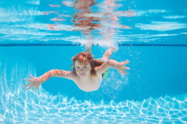 Child in pool in summer day. Underwater boy in the swimming pool. Cute kid boy swimming in pool under water