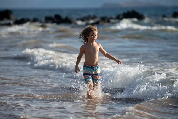 子供たちは海のビーチ沿いの海岸に近い水を介して実行している 少年は海岸沿いを走る 夏休みの残りの子供たち — ストック写真