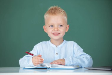 Okuldaki çocuk. Çocuk sınıfta tahtayla ilgili bir şeyler öğreniyor. İlkokulda ders sırasında tahtaya yakın öğrenci portresi.