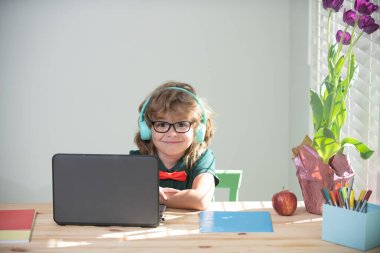 Child boy in headphones using a laptop at home. Homeschooling, online distant learning