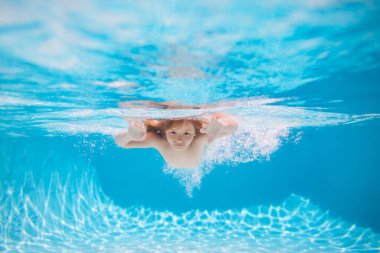 Child swimming underwater in swimming pool. Funny kids boy play and swim in the sea water. Summer kids in water in pool underwater