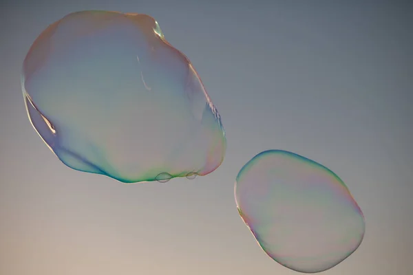 Big bubble flying over blue sky. Huge colorful soap bubbles fly over cloudy sky background