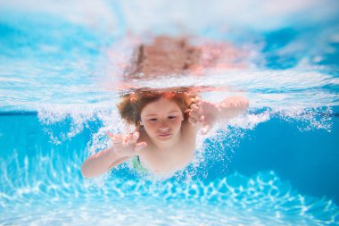 Child boy swim under water in sea. Kid swimming in pool underwater. Happy boy swims in sea underwater, active kid swimming, playing and diving, children water sport. Kids swim on summer vacation
