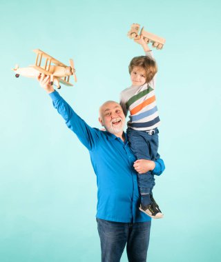 Grandson child and grandfather piggyback with toy plane and wooden truck. Men generation granddad and grandchild