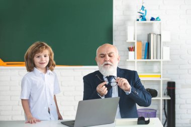 Back to school. Teacher and child. Education and learning concept. Schoolboy in classroom. Old teacher and young pupil