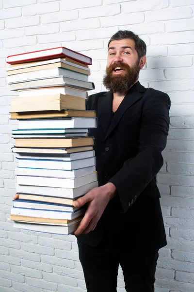 Funny teacher or professor with book stack. Thinking serious mature teacher. Falling books concept. Mature professor, middle aged teacher, bearded fun man. Books stacked fall