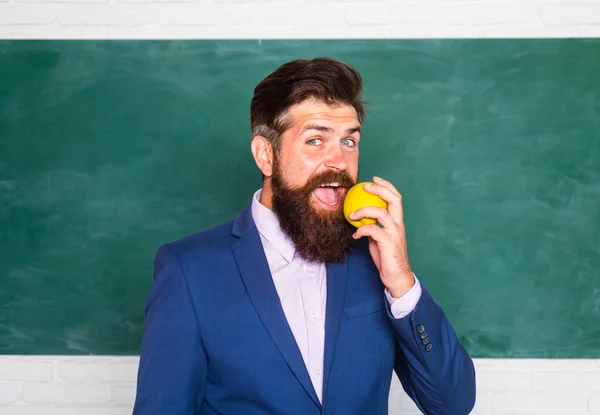 Portrait of a funny teacher or professor near blackboard. Thinking serious mature teacher. Mature professor, middle aged teacher, bearded man