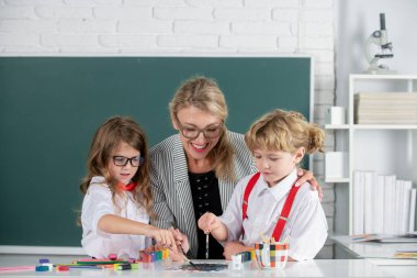 Schoolkids with teacher. Happy children from elementary school study at draw lesson. Teacher and little students portrait, teachers day.Pupils girl and boy with teacher painting at art school