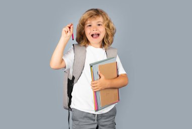 Back to school. Schoolboy with school bag hold book and copybook ready to learn. School children on isolated studio background. Excited kids face, cheerful amazed emotions of school child