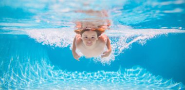 Young boy swim and dive underwater. Under water portrait in swim pool. Child boy diving into a swimming pool. Summer vacation concept