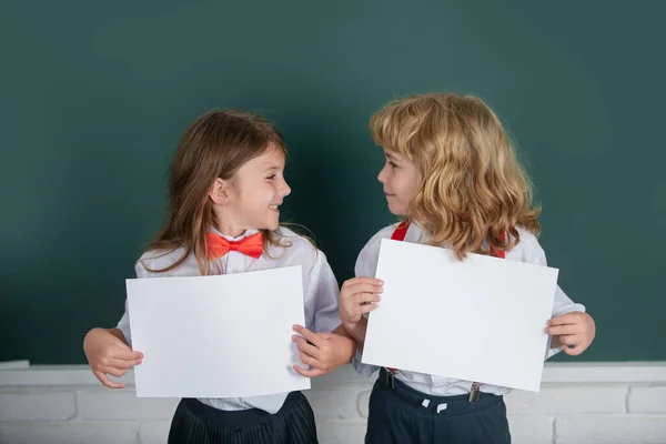 Two Schoolkids Holding White Paper Blank Poster Copy Space Schoolgirl — Fotografia de Stock