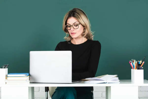 Young teacher or female student with notebook on a blank chalkboard. Female professor at school, ready to start lesson