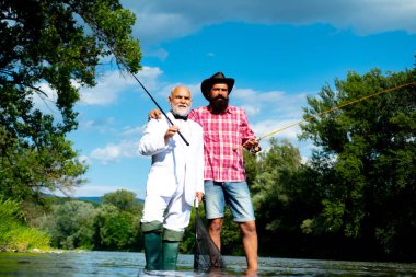 Men fishing. Fishing anglers in river water. Old and young fisherman