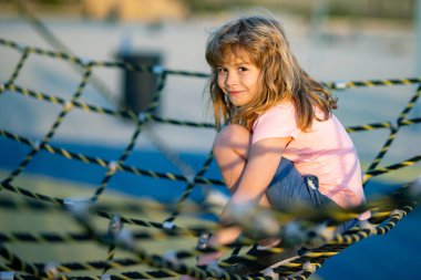 Child climbing the net. Little boy climbs up the ladder on the playground. Child climbs up the ladder. Little caucasian boy hanging on the monkey bar by his hand to exercise at outdoor playground
