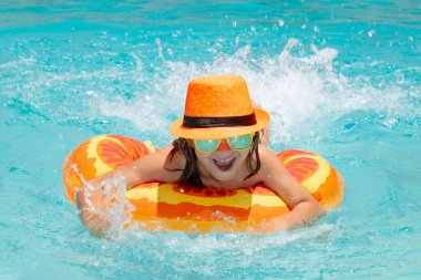 Child boy boy relaxing in pool. Kid swimming in water pool. Summer kids activity, watersports. Fashion summer tanned kid in hat and suglasses
