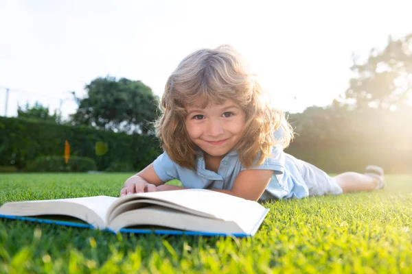 Child relax in the holiday. Kid read books on grass background