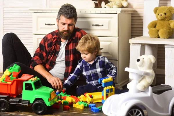 Father and son create toys from bricks. Dad and kid build of plastic blocks. Father and son playing toys wooden blocks on floor in living room