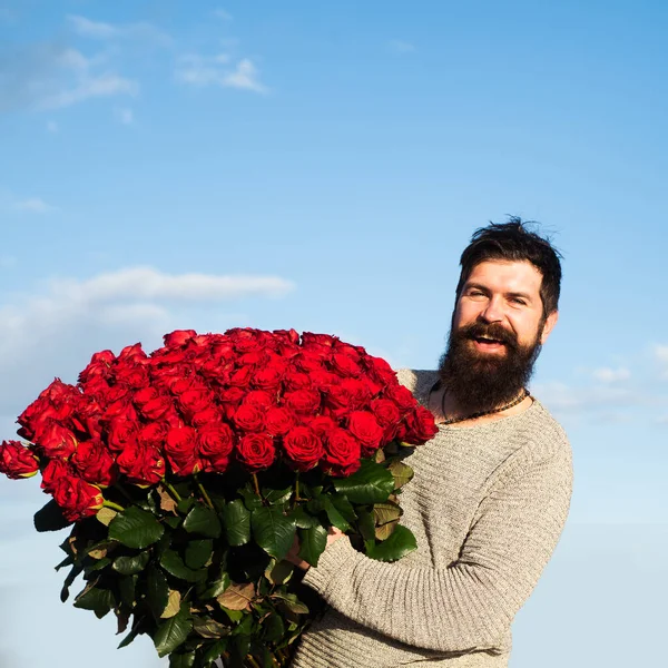 Man with bouquet of flowers. Happy man holds a large bouquet of red roses, propose to boyfriend on date. Romantic guy celebrate valentines day