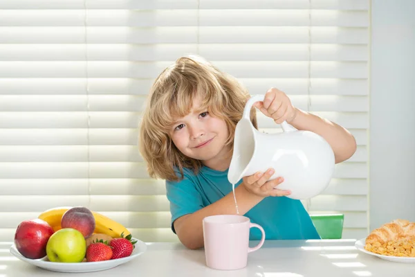 Kid boy pouring whole cows milk. Kid eating healthy food vegetables. Breakfast with milk, fruits and vegetables. Child eating during lunch or dinner