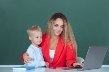 Mother and son learning. Teacher helping elementary school pupils in computer class, learning with laptop. Teacher helping school kids in classroom at school