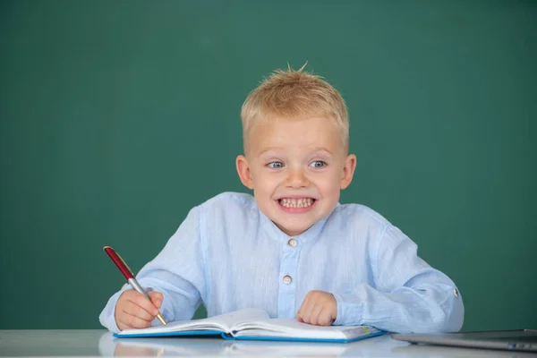 学校の教室で小学校の勉強の小さな学生の面白い顔 クラスのノートに書く子供 — ストック写真