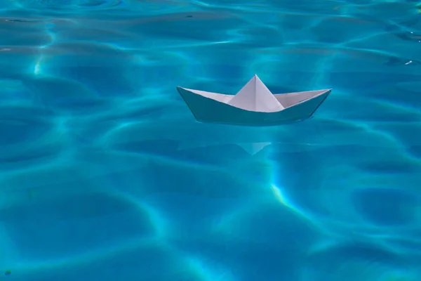 Cruise liner paper art. Paper boat sailing away on sea surface water background. Origami toy ship as a symbol of discovery, mission, freedom and voyage. Paper craft and origami