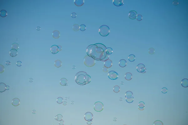 Big bubble flying over blue sky. Huge colorful soap bubbles fly over cloudy sky background