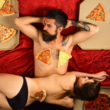 Evde yatakta pizza yiyen seksi bir çift. Sevgiyle pizza. Aşık çift yatakta pizza yemekten hoşlanır. Seksi kadın eve pizza sipariş etti.