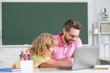 Öğretmen, ilkokuldan çocuk öğrenciye sınıfta yardım ediyor. Öğretmen ve okul çocuğu okulda öğreniyor. İlkokul öğrencisi, zeki öğrenci.