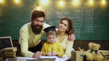 Genç bir aile ders çalışıyor. Sevimli küçük çocuk ailesinden öğreniyor. Anne, baba ve çocuklar evde resim çiziyorlar.